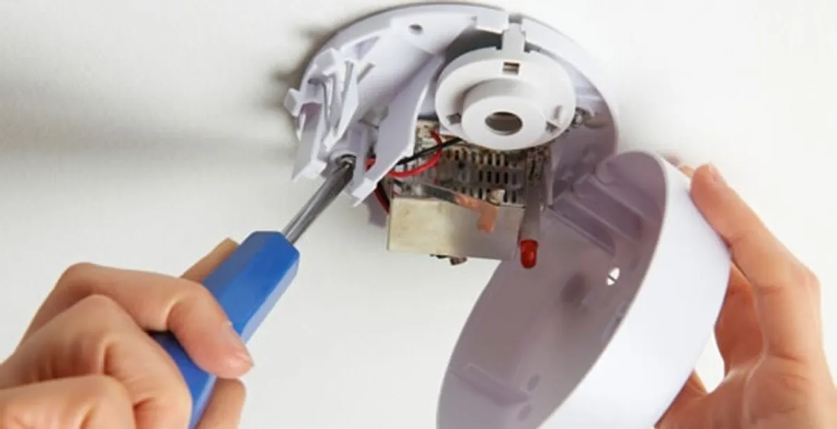 Certified technician wiring smoke detector during installation in Boca Raton, FL